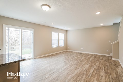 A spacious room with wooden flooring and a large window.