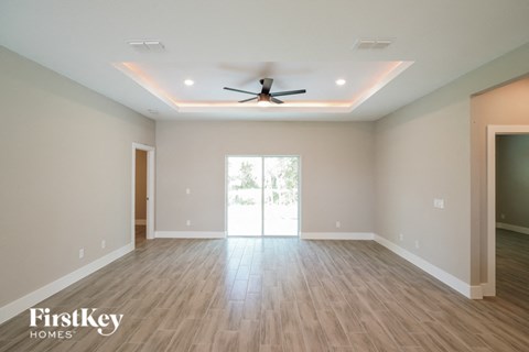 A spacious room with a ceiling fan and wooden flooring.