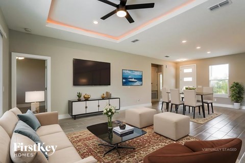 A living room with a brown couch and a television on the wall.