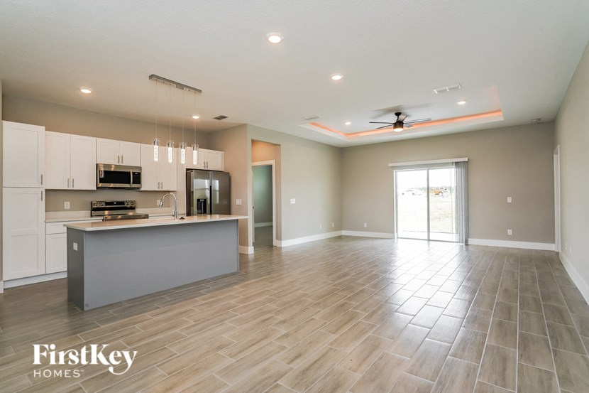 A spacious kitchen and living room with wooden flooring and a ceiling fan.