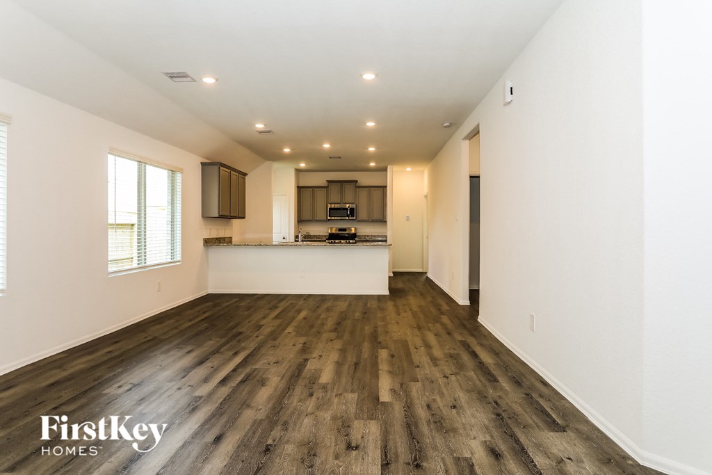 the living room and kitchen of an apartment with hardwood floors and white walls