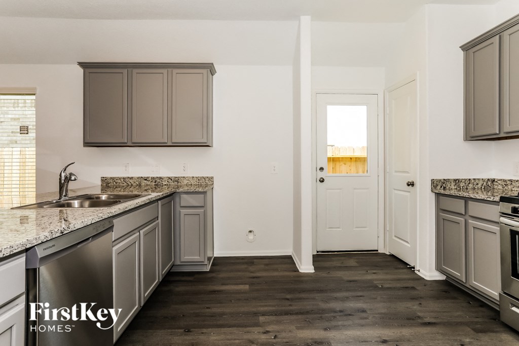 a kitchen with stainless steel appliances and gray cabinets and a white door