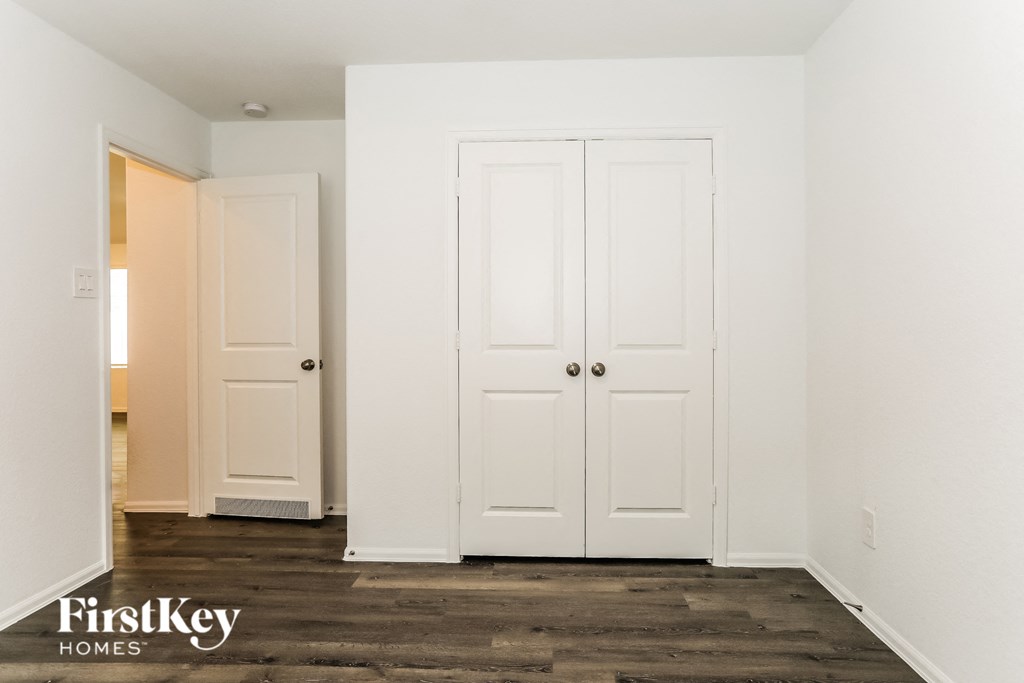 a bedroom with two closet doors and a wood floor