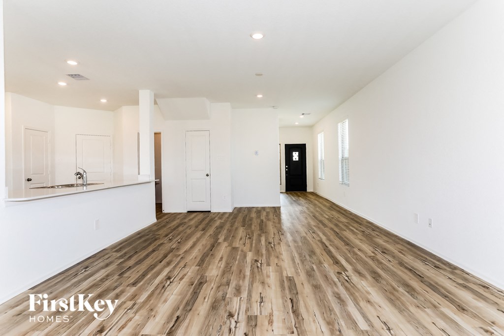 a renovated living room and kitchen with white walls and wood floors