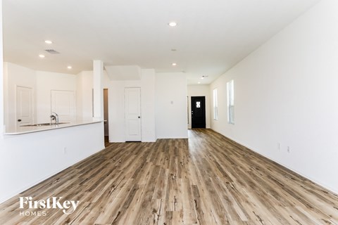 a renovated living room and kitchen with white walls and wood floors