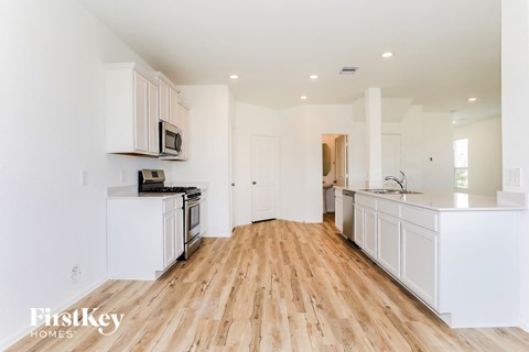 a white kitchen with wood floors and white cabinets