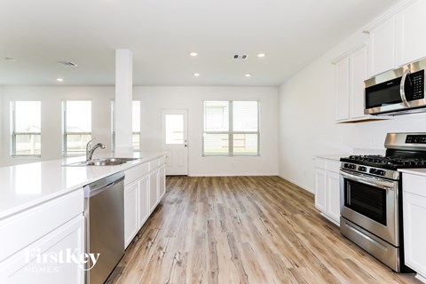 a white kitchen with wood floors and white cabinets and stainless steel appliances