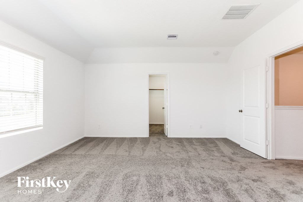a bedroom with white walls and carpet and a door to a closet