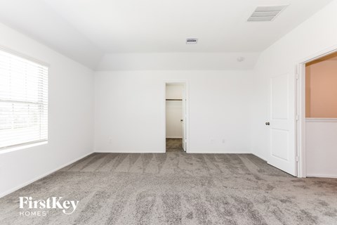 a bedroom with white walls and carpet and a door to a closet