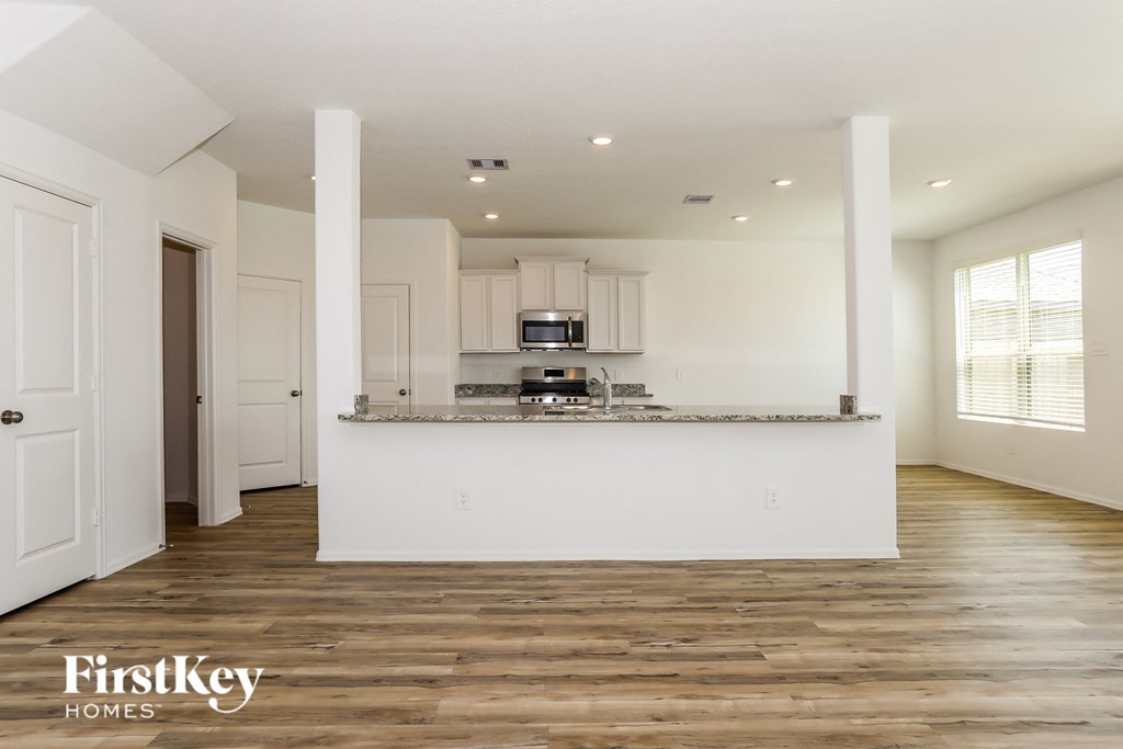 the kitchen and living room of a new home with white walls and wood flooring