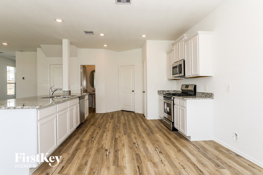 a kitchen with white cabinets and wood flooring and