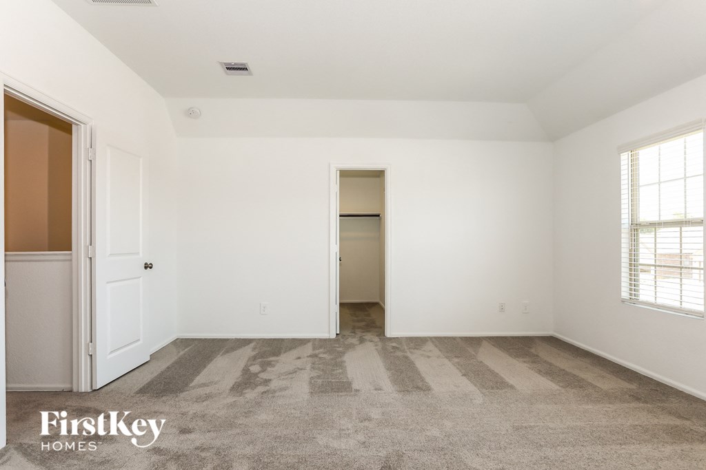 a bedroom with white walls and carpet and a door to a closet