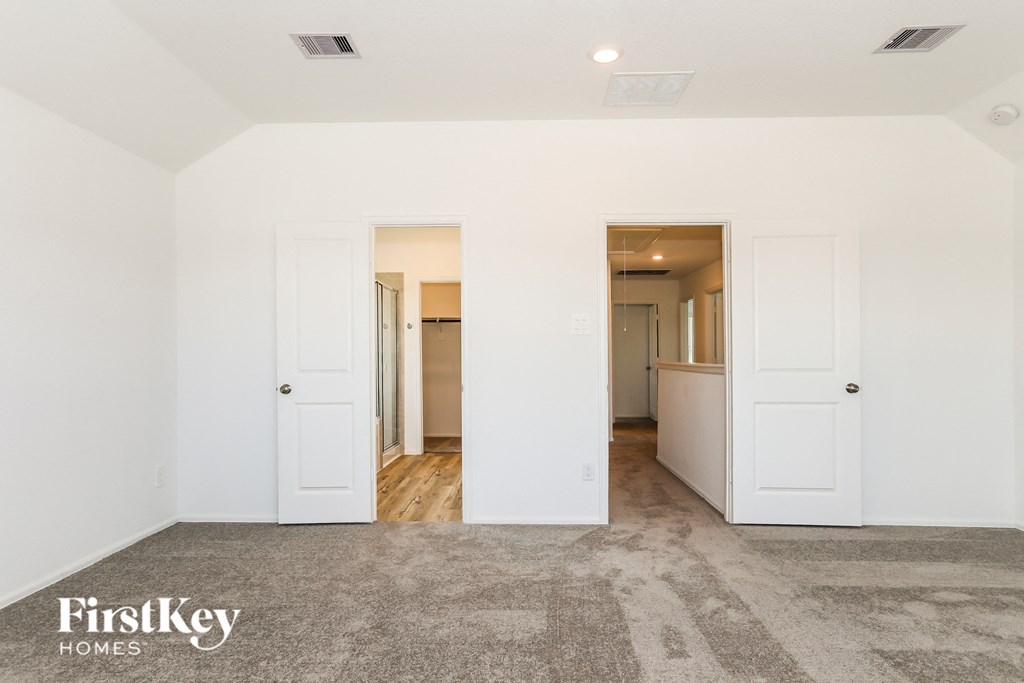 a living room with white doors and a hallway to a kitchen