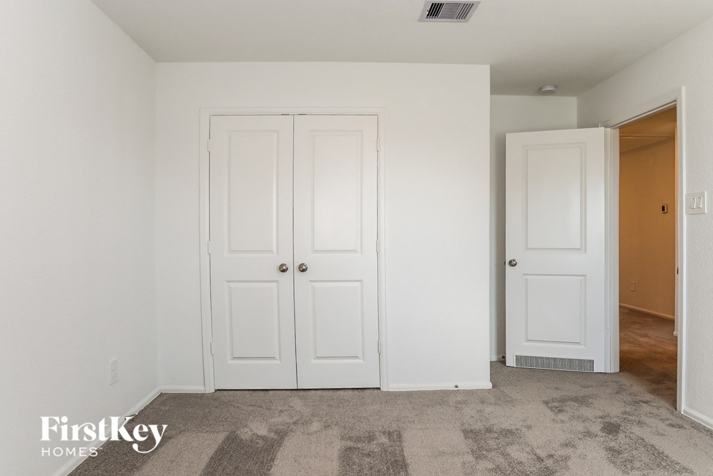 a bedroom with two closet doors and a door to a hallway