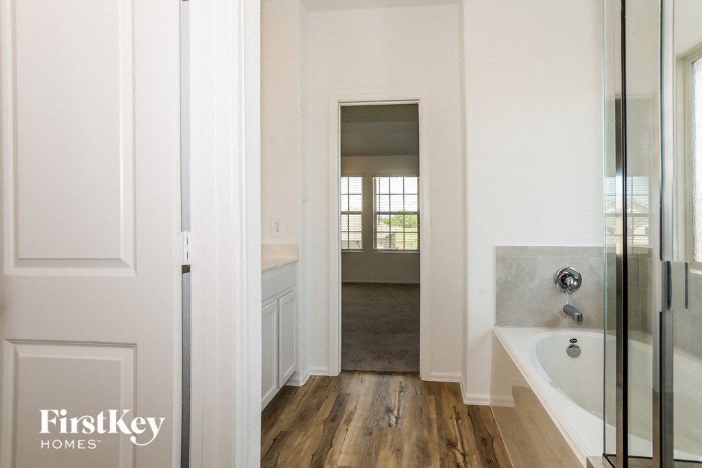 a bathroom with a sink and a shower and a door to a room