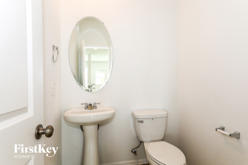 a white bathroom with a sink toilet and a mirror