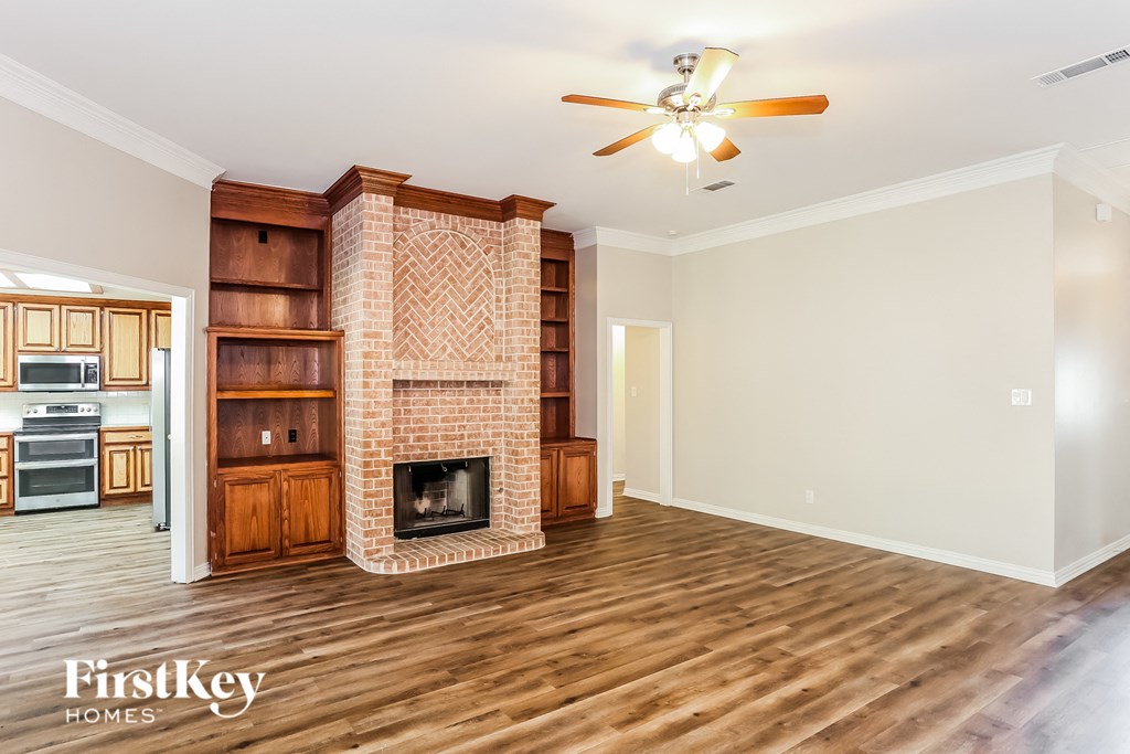 a living room with a brick fireplace and wooden floors