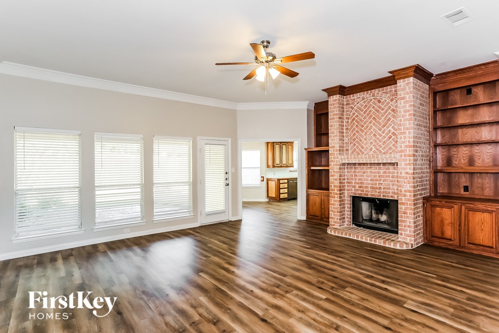 a living room with a brick fireplace and a ceiling fan