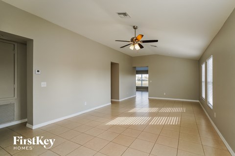 an empty living room with a ceiling fan and tiled floors