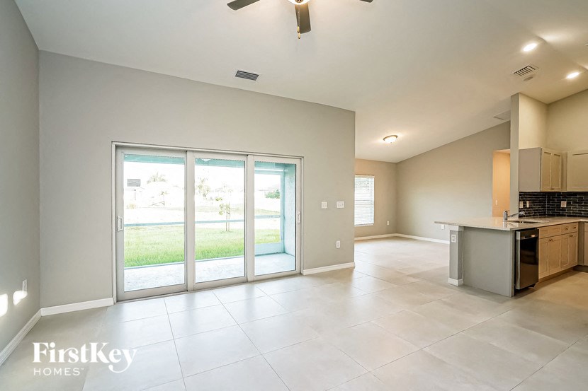 A spacious kitchen and living room with a view of the backyard through the sliding glass doors.