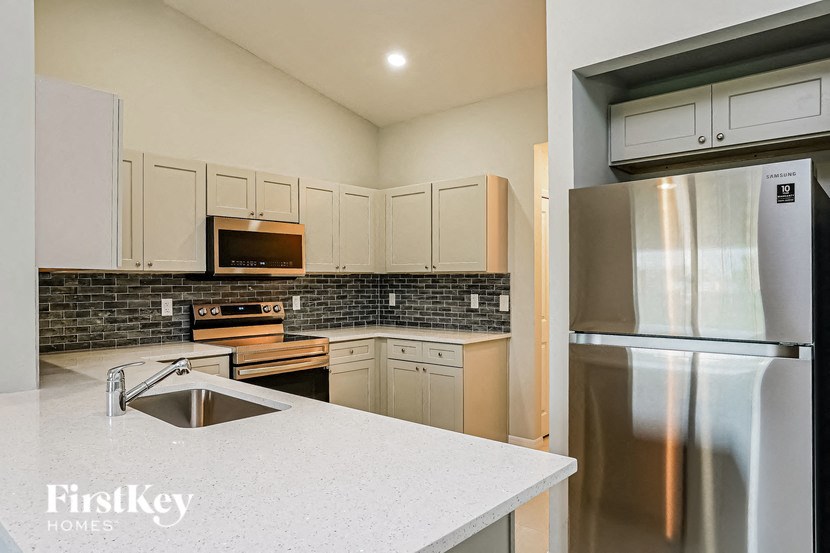 A kitchen with a stainless steel refrigerator and a sink.