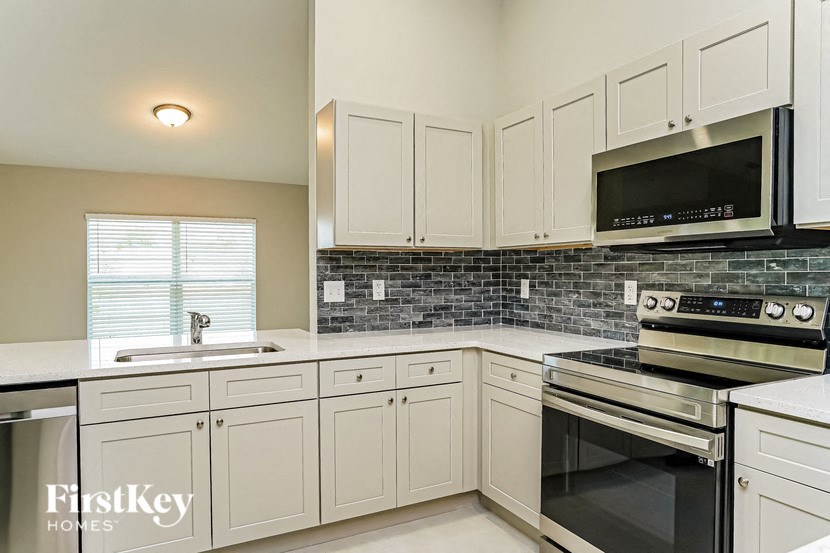 A kitchen with white cabinets and a black microwave above the stove.