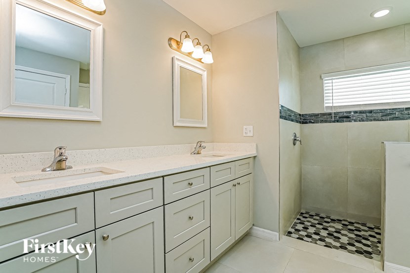 A bathroom with a sink, mirror, and shower.