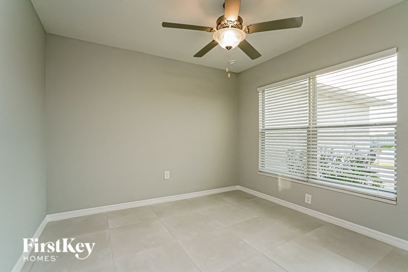 A room with a ceiling fan and a window with blinds.