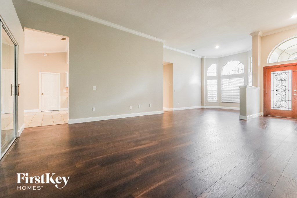 A spacious room with wooden floors and a red door.