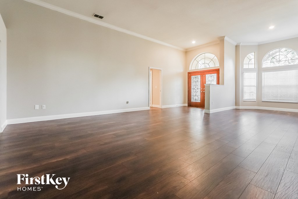 A spacious room with wooden floors and a red door.