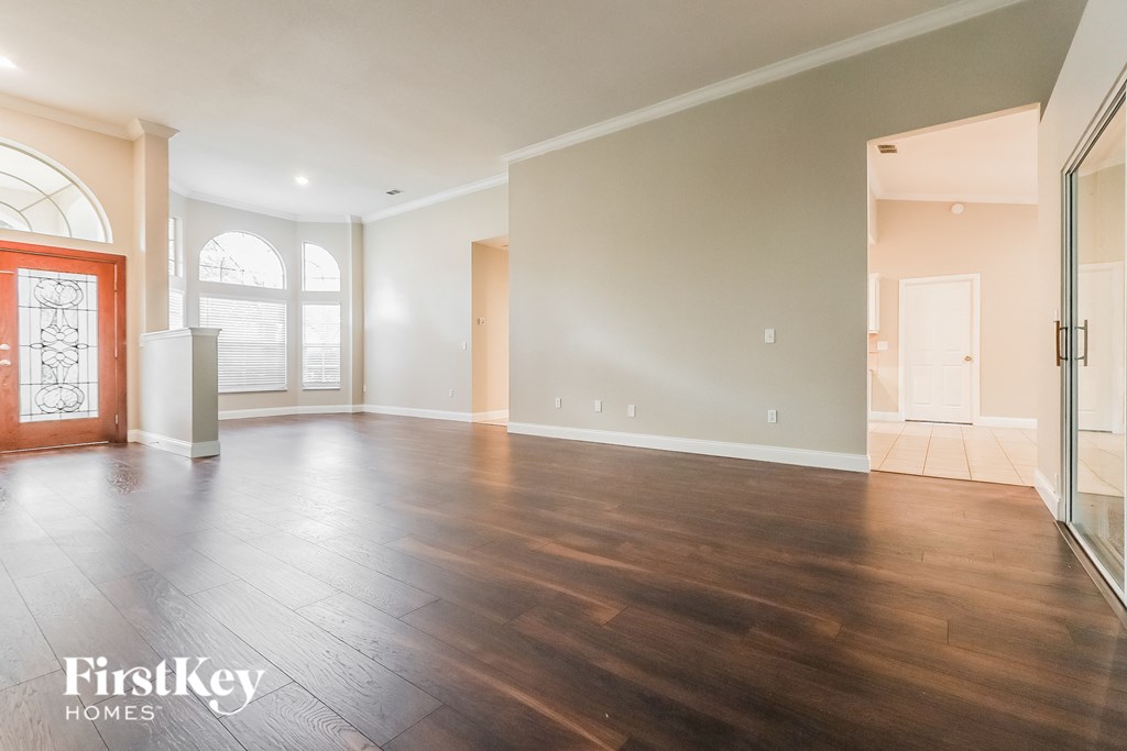 A spacious room with wooden floors and a red door.