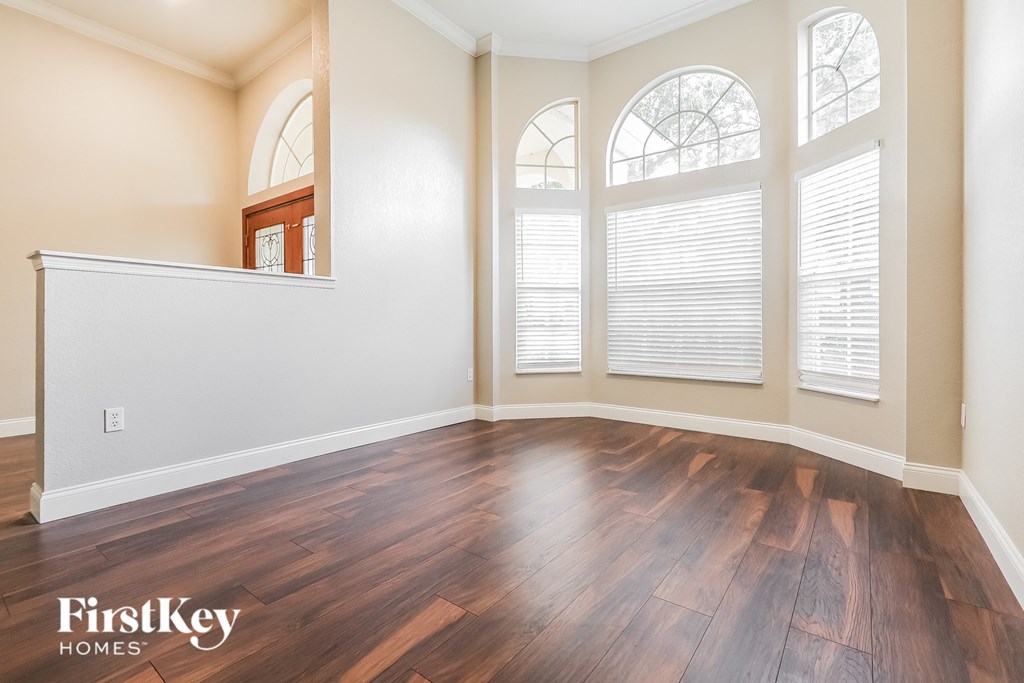A room with wooden flooring and a window with blinds.