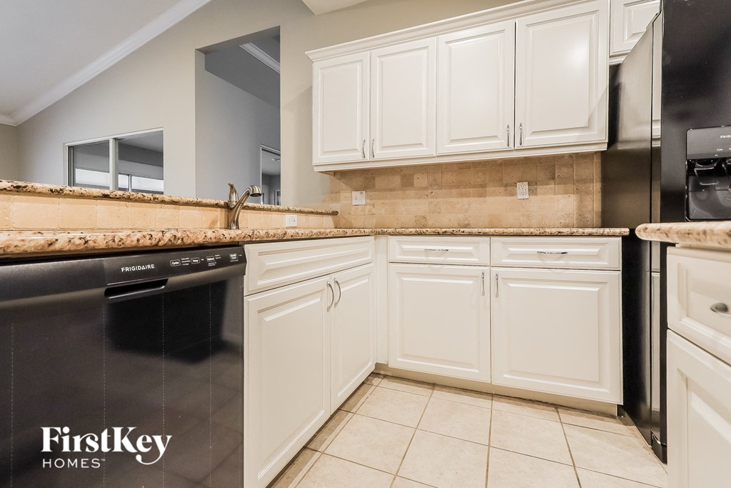 A kitchen with white cabinets and a black dishwasher.