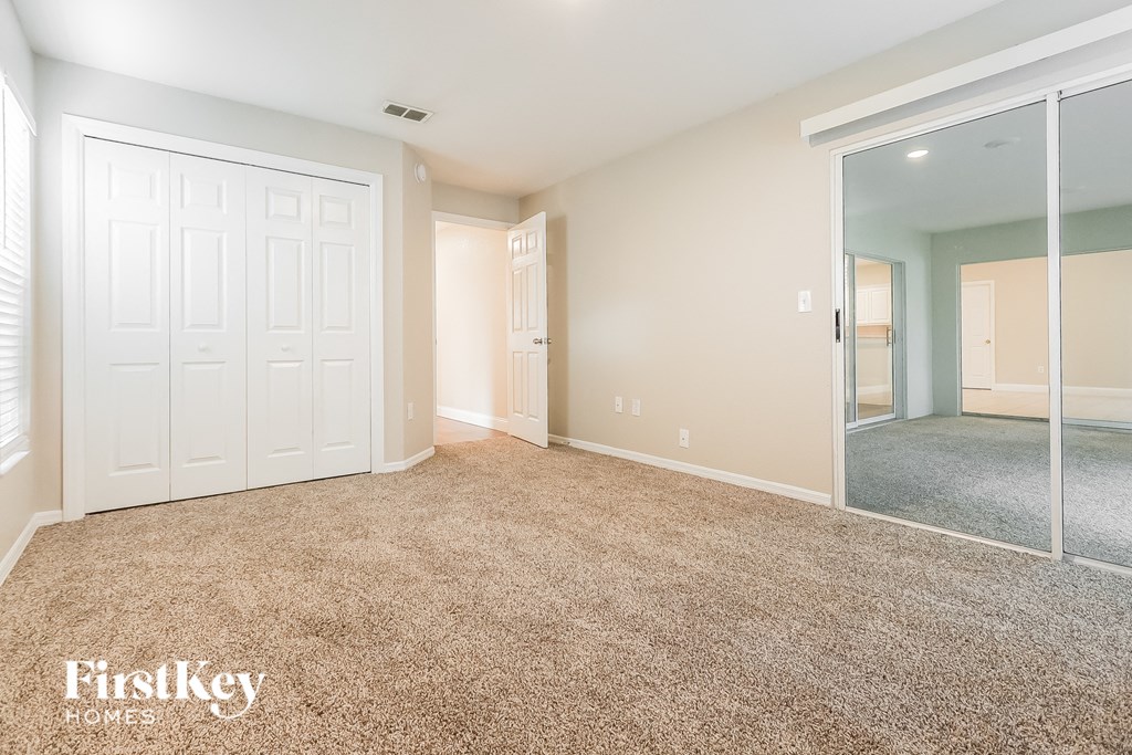A room with a carpeted floor and a sliding glass door leading to a balcony.