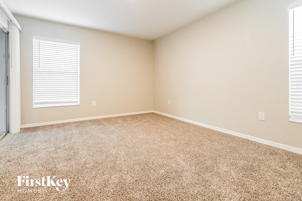 A room with a carpeted floor and a window with blinds.