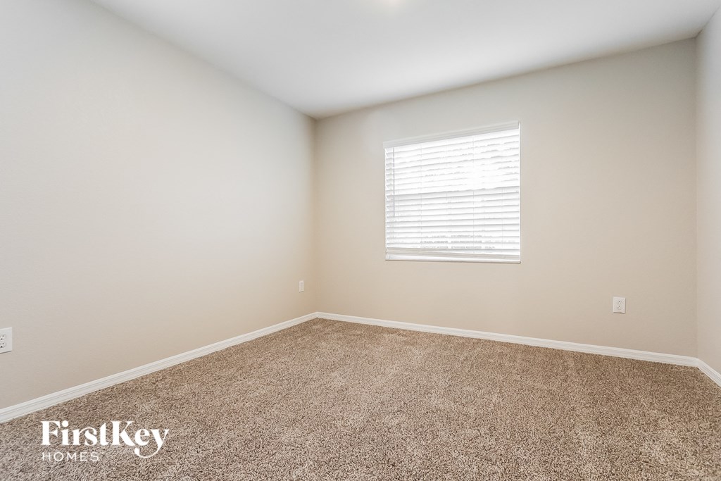A carpeted room with a window and a FirstKey Homes logo.