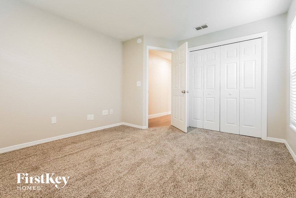 A carpeted room with a white door and a window.