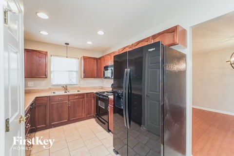 A kitchen with a black refrigerator and wooden cabinets.