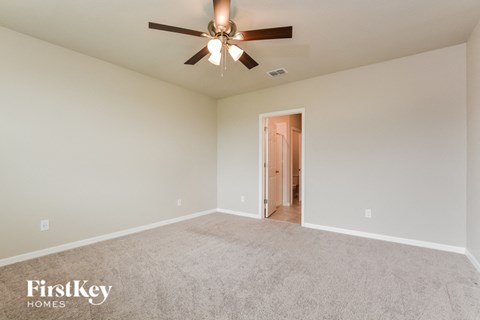 the spacious living room with ceiling fan and carpet