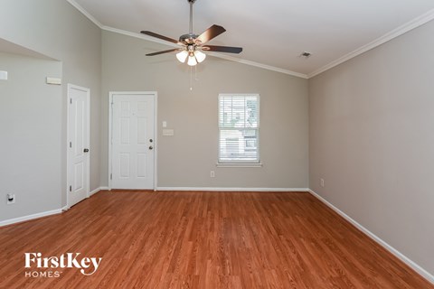 an empty living room with wood floors and a ceiling fan