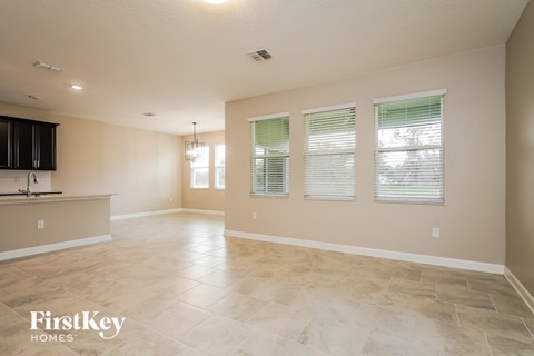 an empty living room and kitchen with a sink and window