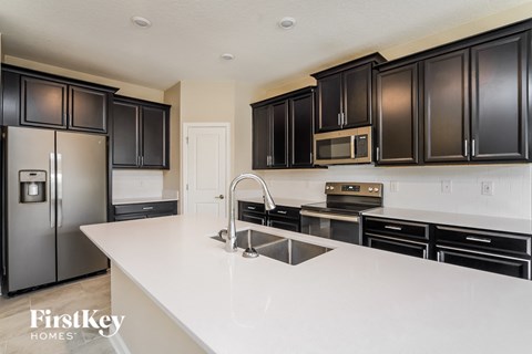 a kitchen with black cabinets and white countertops and stainless steel appliances