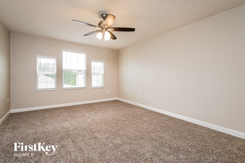 the master bedroom is spacious and clean with carpeting and a ceiling fan