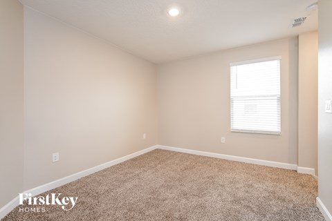 the spacious living room with carpeting and a window