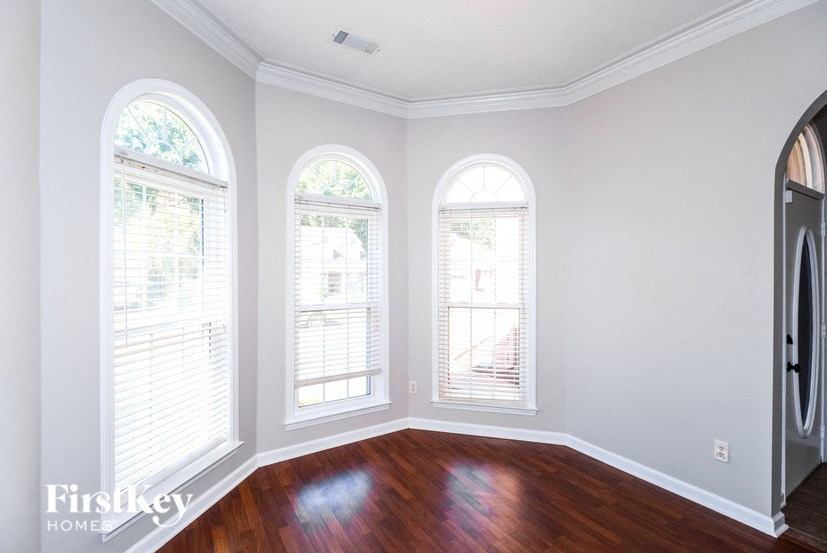 a living room with three windows and a hard wood floor