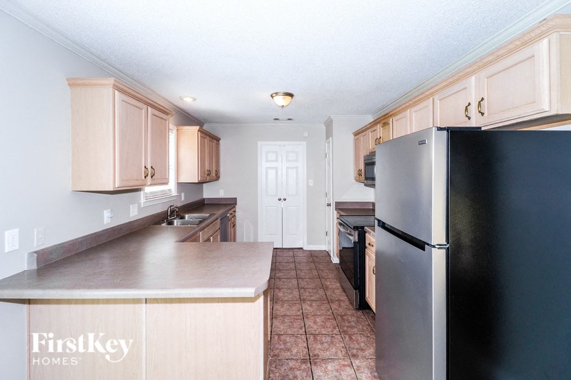 a kitchen with white cabinets and a black refrigerator