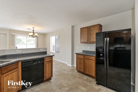 A kitchen with a black fridge and wooden cabinets.