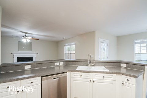 a kitchen with white cabinets and a sink and a ceiling fan