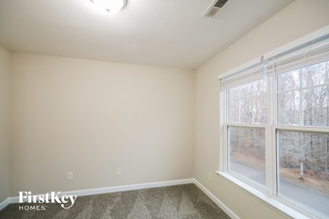 a bedroom with two large windows and a carpeted floor