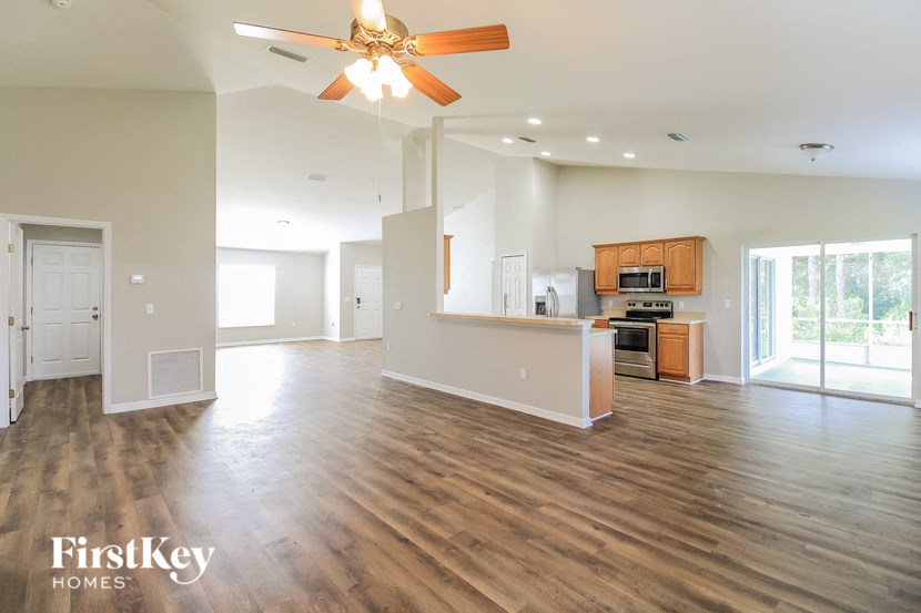 A spacious living room with a ceiling fan and wooden flooring.